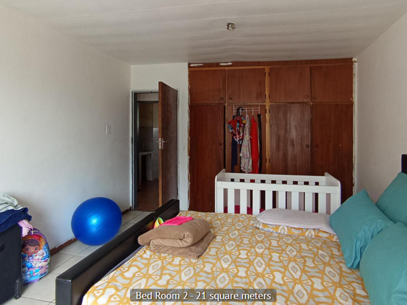 A bedroom featuring built-in wooden cupboards and tiled flooring, offering a functional space with potential for cosmetic updates.
