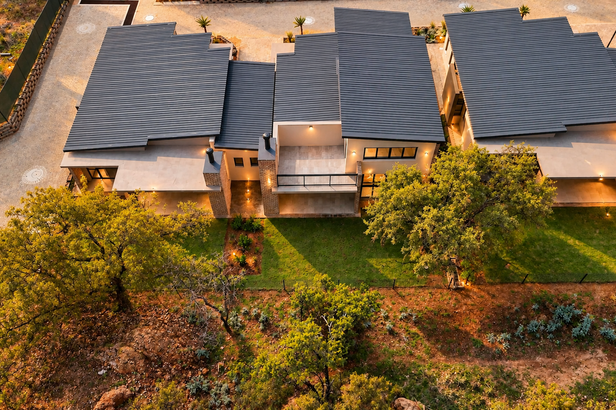 Aerial view of modern retirement village units featuring corrugated metal roofing, brick accents, paved driveways, and landscaped outdoor spaces.