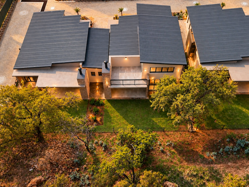Aerial view of modern retirement village units featuring corrugated metal roofing, brick accents, paved driveways, and landscaped outdoor spaces.