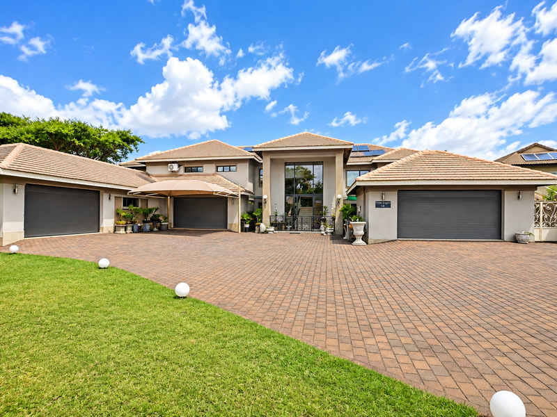 Spacious front exterior featuring a large paved driveway, triple garage, and well-maintained facade with solar panels and modern architectural details.