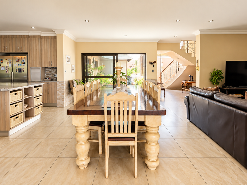 Spacious open-plan living area featuring a modern kitchen with island, dining space, and direct access to the patio, complemented by neutral tiled flooring.