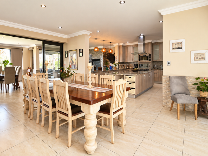 Spacious open-plan living and dining area featuring a modern kitchen with a central island, stone tile flooring, and seamless access to the outdoor patio.