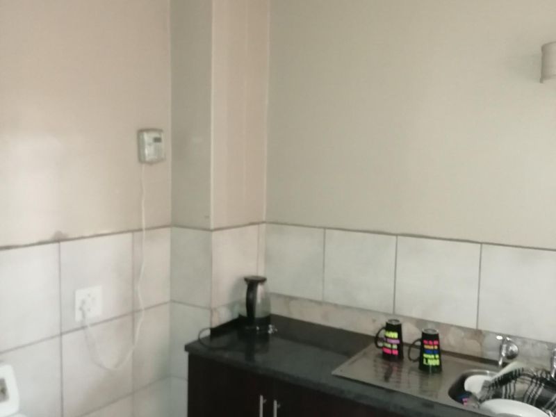 A compact kitchen area featuring dark cabinetry, granite countertops, and a tiled splashback, requiring minor maintenance and cosmetic updates.