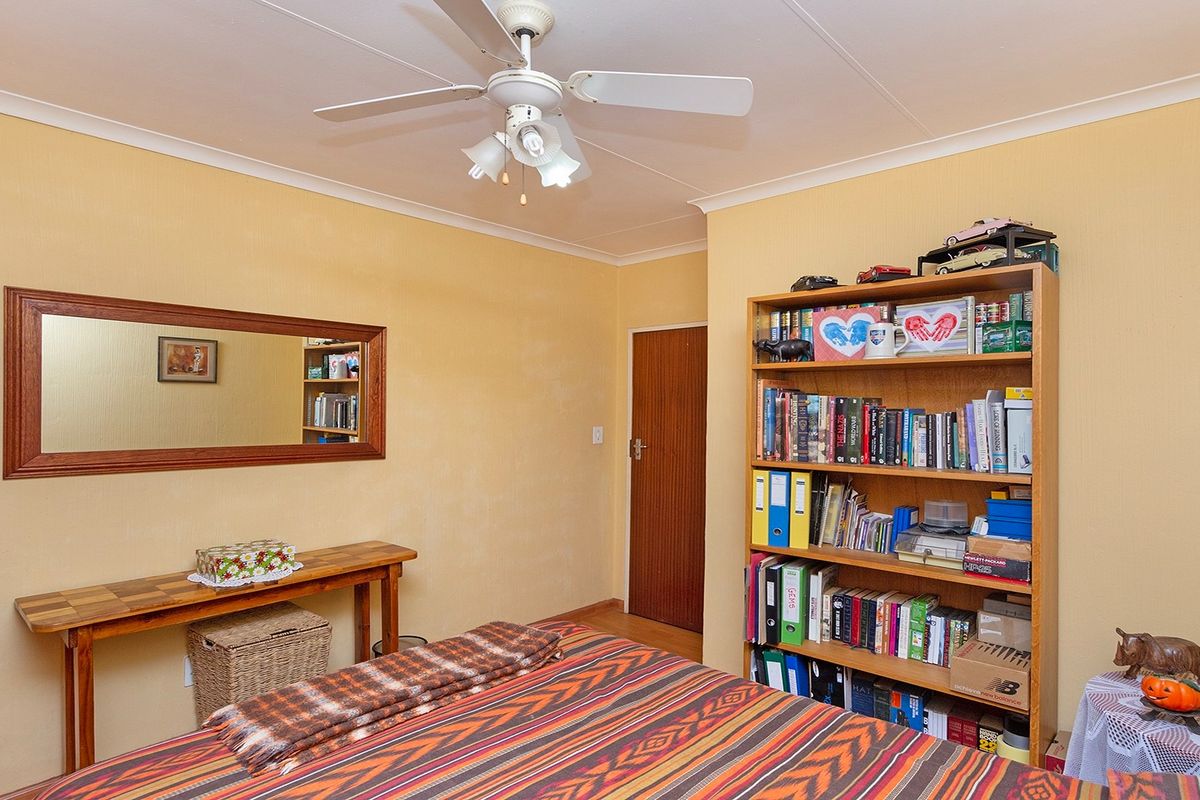 A bedroom featuring a ceiling fan, neutral wall finishes, and a standard interior door.