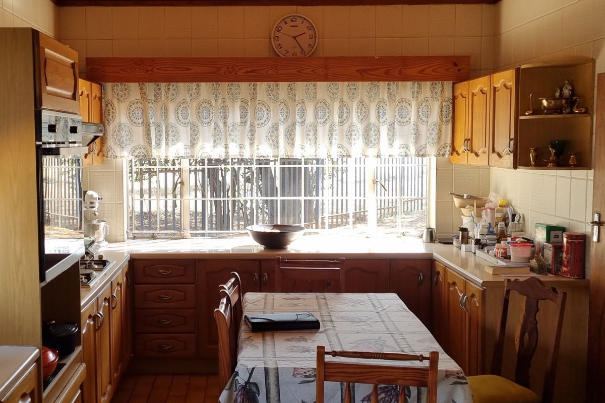 A traditional kitchen featuring wooden cabinetry, built-in oven, hob, and a timber-clad ceiling, offering a functional layout with ample natural light.