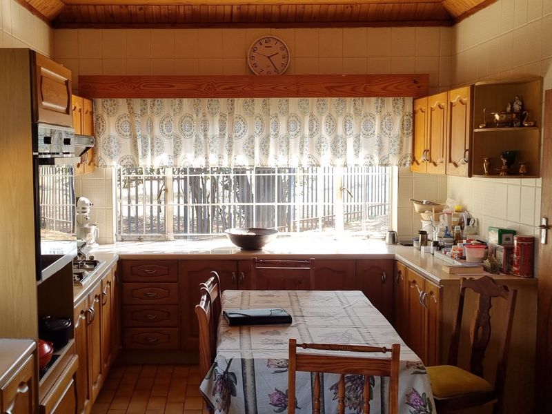 A traditional kitchen featuring wooden cabinetry, built-in oven, hob, and a timber-clad ceiling, offering a functional layout with ample natural light.
