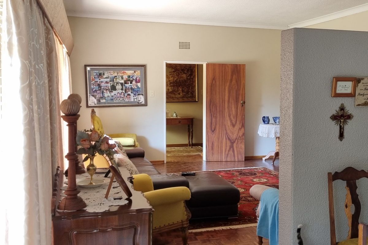 A living room featuring classic parquet flooring, a textured partition wall, and a wooden door leading to an adjacent space.