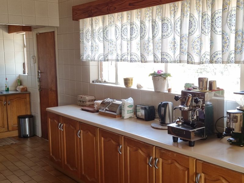 A functional kitchen featuring wooden cabinetry, laminate countertops, and tiled wall finishes, offering a traditional aesthetic with ample workspace.