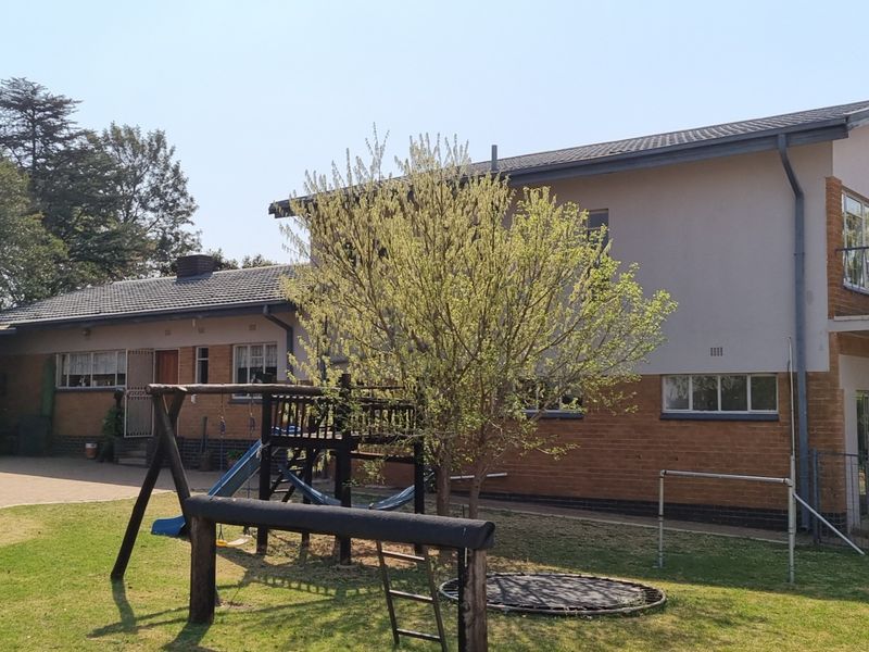 Rear view of the farm property featuring a brick and plastered facade, tiled roof, and an adjacent paved patio area.