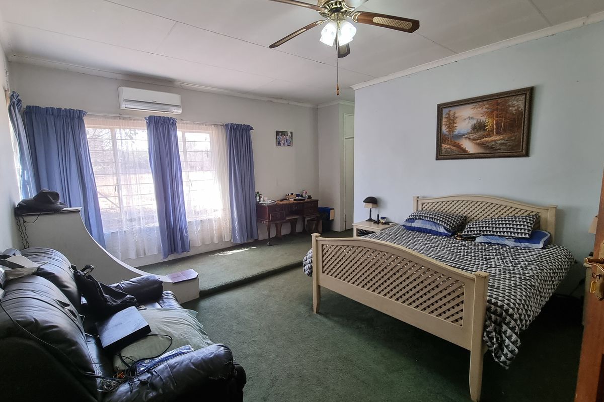Spacious bedroom featuring a raised platform area, split-system air conditioning unit, and large windows allowing for natural light.