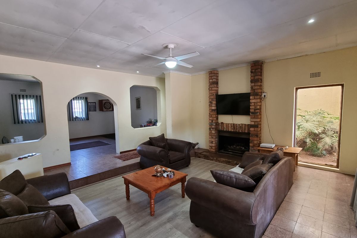 Spacious living room featuring a brick fireplace, ceiling fan, and arched wall openings leading to adjacent living areas.