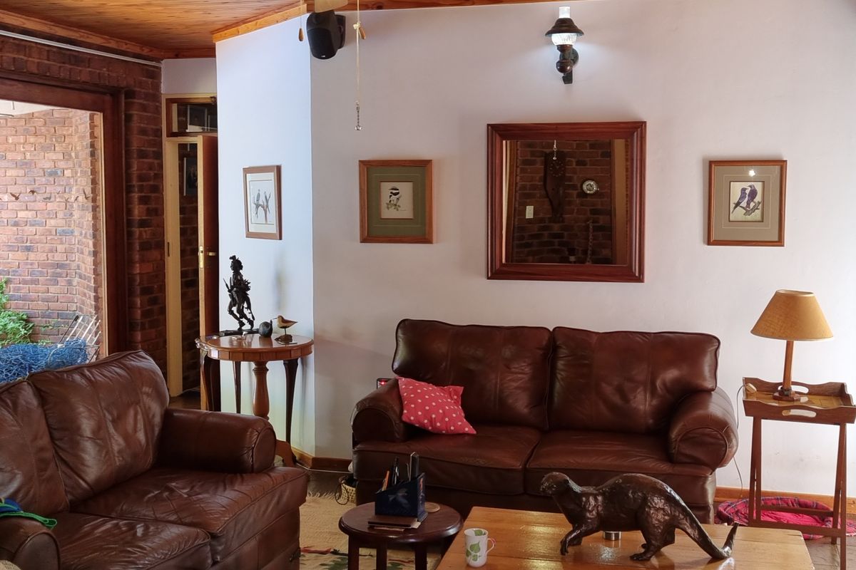 A cozy living room featuring exposed brick walls, timber-clad ceiling, and direct access to an outdoor patio area.