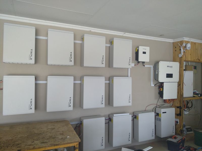 A dedicated utility space featuring a comprehensive wall-mounted solar battery storage system and multiple solar inverters for efficient energy management.