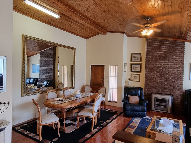 Spacious open-plan living and dining area featuring a vaulted timber ceiling, a prominent brick fireplace with an insert, and tiled flooring throughout.
