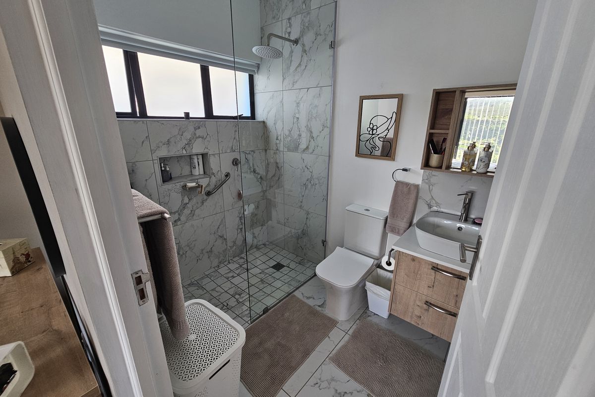 Modern bathroom featuring a walk-in shower with marble-look tiling, a contemporary vanity with vessel sink, and a wall-mounted mirror cabinet.
