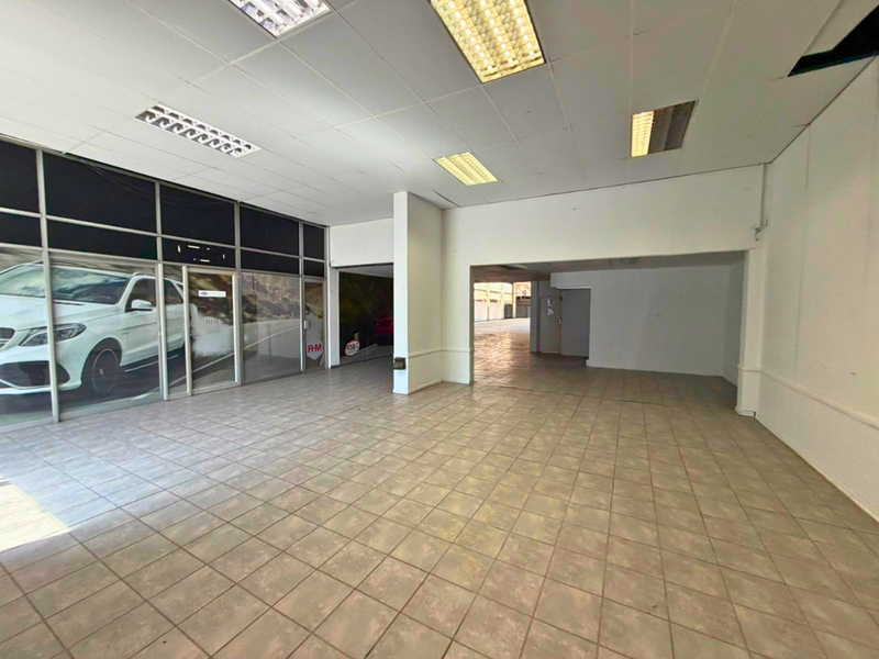 Spacious open-plan industrial showroom or retail space featuring tiled flooring, large glass frontage, and suspended ceiling with integrated lighting.