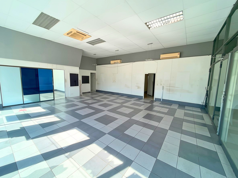 Spacious, empty industrial office unit featuring tiled flooring, suspended ceilings with recessed lighting, and integrated split-system air conditioning units.