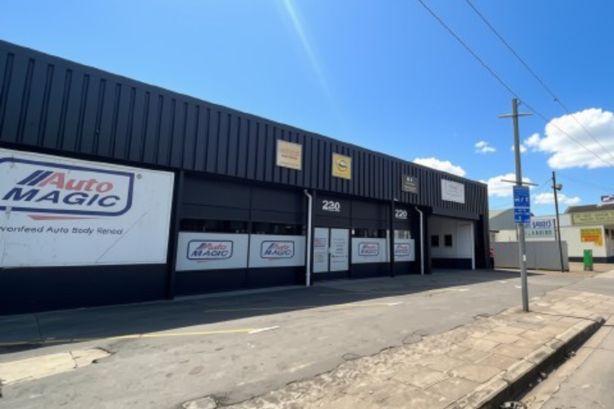 Front elevation of an industrial commercial property featuring metal cladding, roller shutter access, and paved frontage.