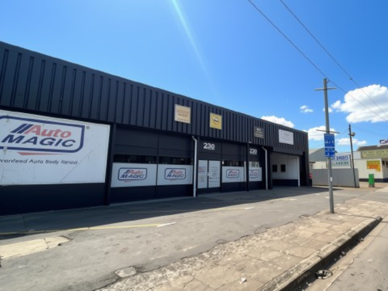 Front elevation of an industrial commercial property featuring metal cladding, roller shutter access, and paved frontage.