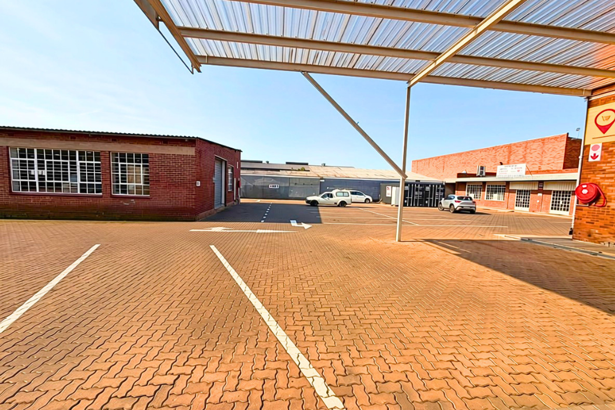 Commercial property exterior featuring a paved parking area with a covered parking structure and brick building facades.