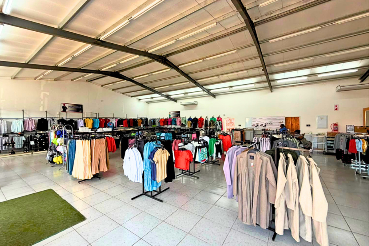 Spacious commercial retail floor featuring high exposed steel roof trusses, bright fluorescent lighting, and durable tiled flooring throughout the open-plan layout.