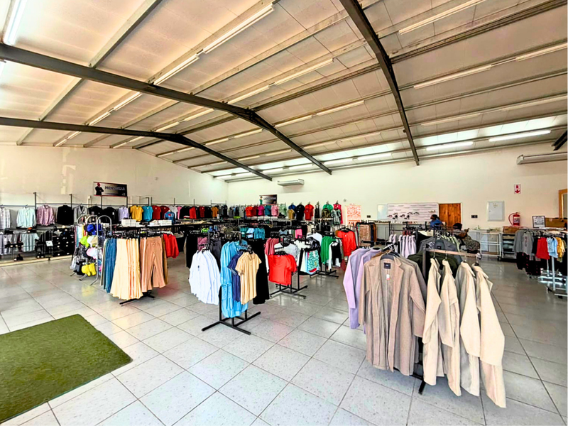 Spacious commercial retail floor featuring high exposed steel roof trusses, bright fluorescent lighting, and durable tiled flooring throughout the open-plan layout.