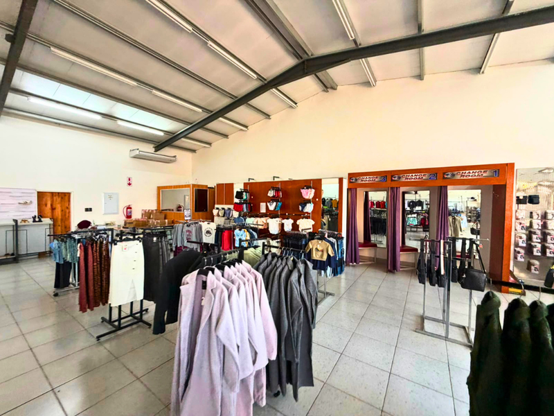 Commercial retail space featuring high ceilings with exposed steel trusses, tiled flooring, and integrated changing room facilities.