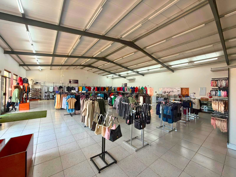 Spacious open-plan commercial retail space featuring high ceilings with exposed steel trusses, tiled flooring, and integrated lighting, suitable for various retail operations.