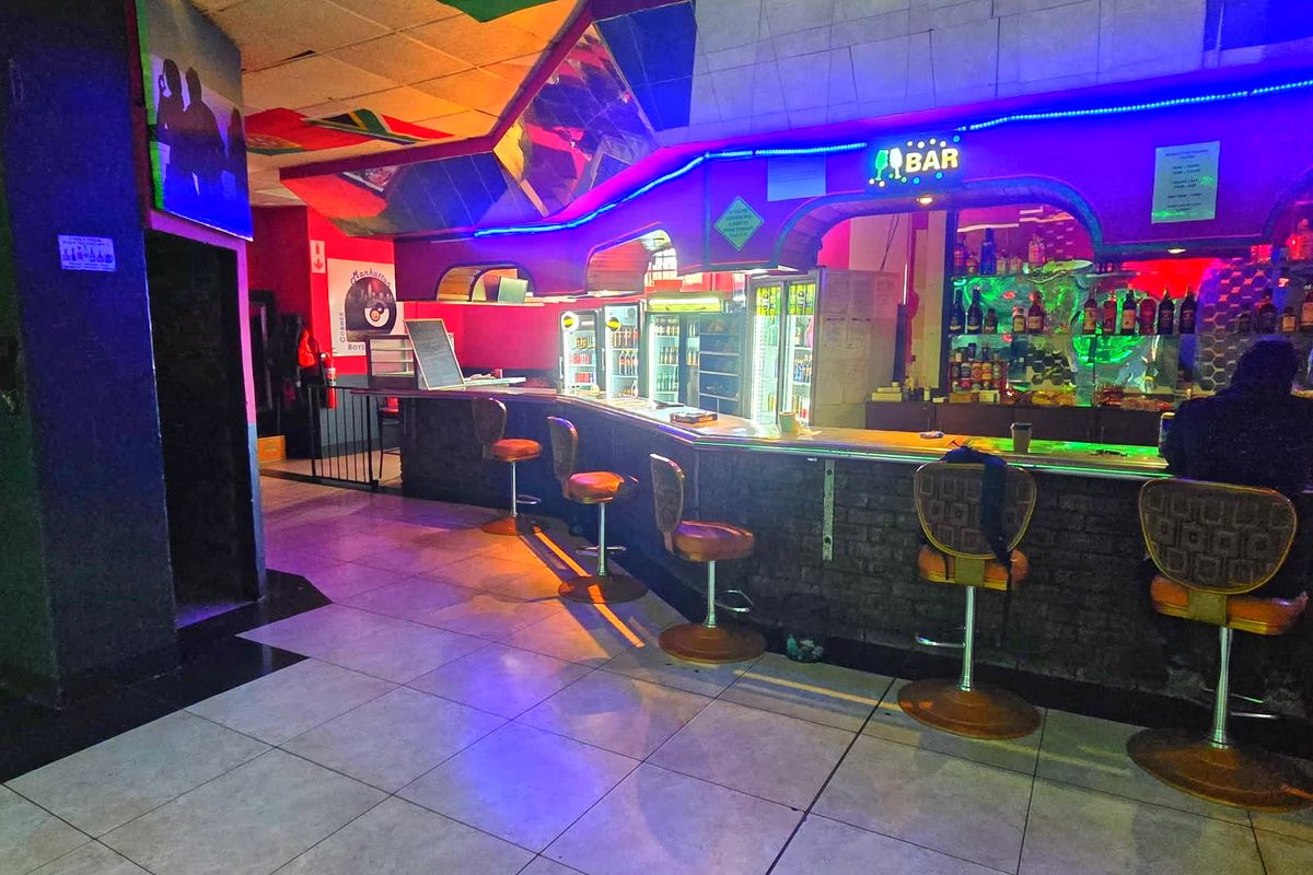 A commercial bar area featuring a built-in counter, tiled flooring, and integrated neon lighting, suitable for hospitality or entertainment use.