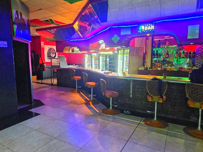 A commercial bar area featuring a built-in counter, tiled flooring, and integrated neon lighting, suitable for hospitality or entertainment use.