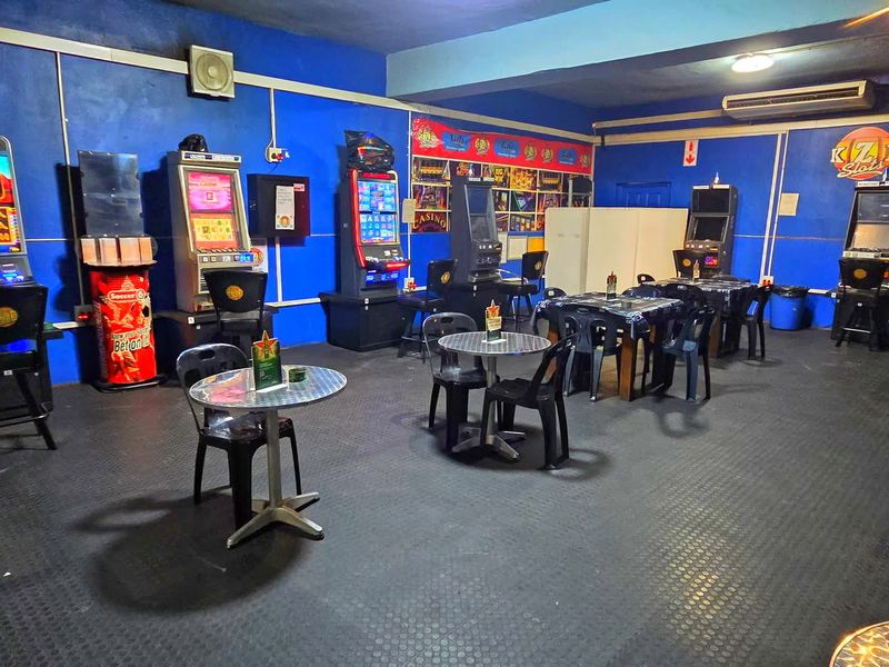 Commercial gaming area featuring rubber flooring, wall-mounted air conditioning, and multiple gaming terminals in a functional open-plan layout.