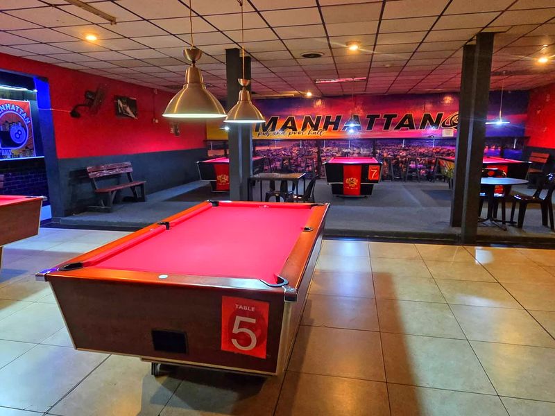 Spacious commercial pool hall featuring tiled flooring, suspended ceiling with recessed lighting, and multiple built-in structural support columns.
