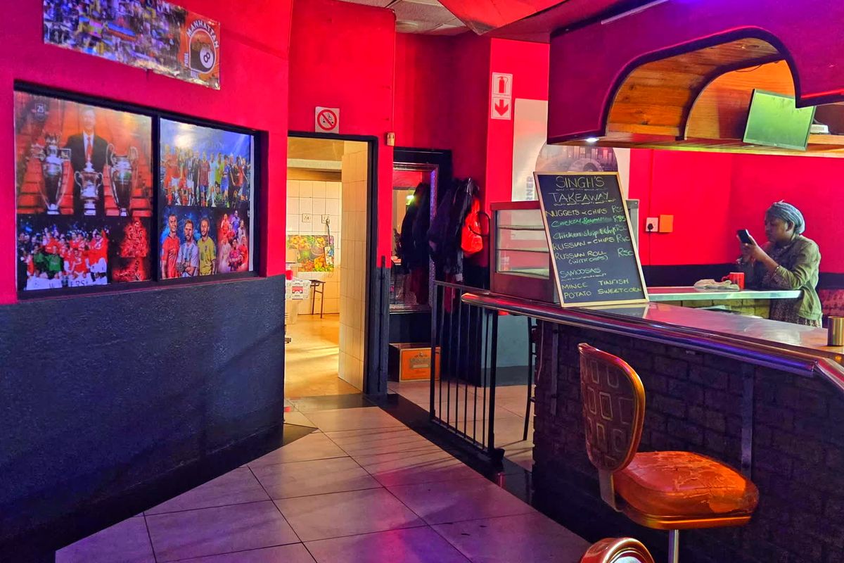Commercial bar area featuring a brick-base counter, tiled flooring, and an overhead bulkhead, currently set up for food service.