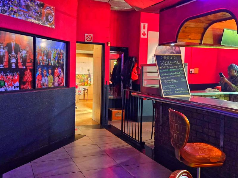 Commercial bar area featuring a brick-base counter, tiled flooring, and an overhead bulkhead, currently set up for food service.