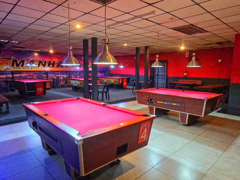 Spacious commercial sports facility featuring tiled flooring, suspended ceiling with integrated lighting, and multiple pool tables for recreational use.