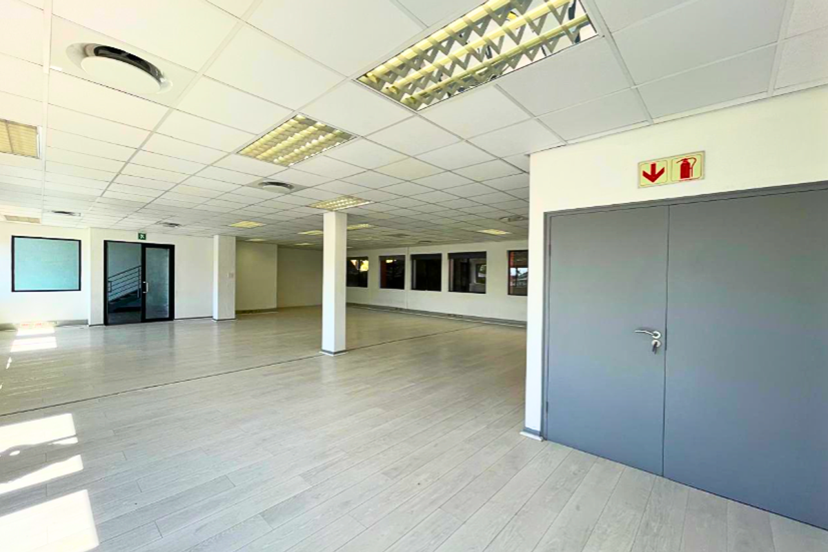 Spacious, open-plan office area featuring a suspended ceiling, recessed lighting, and durable laminate flooring, providing a clean and versatile workspace.
