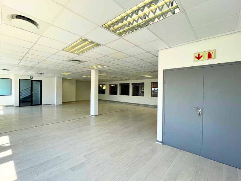 Spacious, open-plan office area featuring a suspended ceiling, recessed lighting, and durable laminate flooring, providing a clean and versatile workspace.