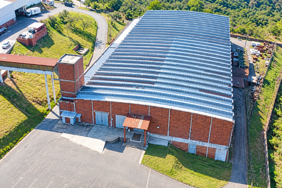 Aerial view of a large industrial warehouse facility featuring a corrugated metal roof, brick exterior, and dedicated loading access areas.