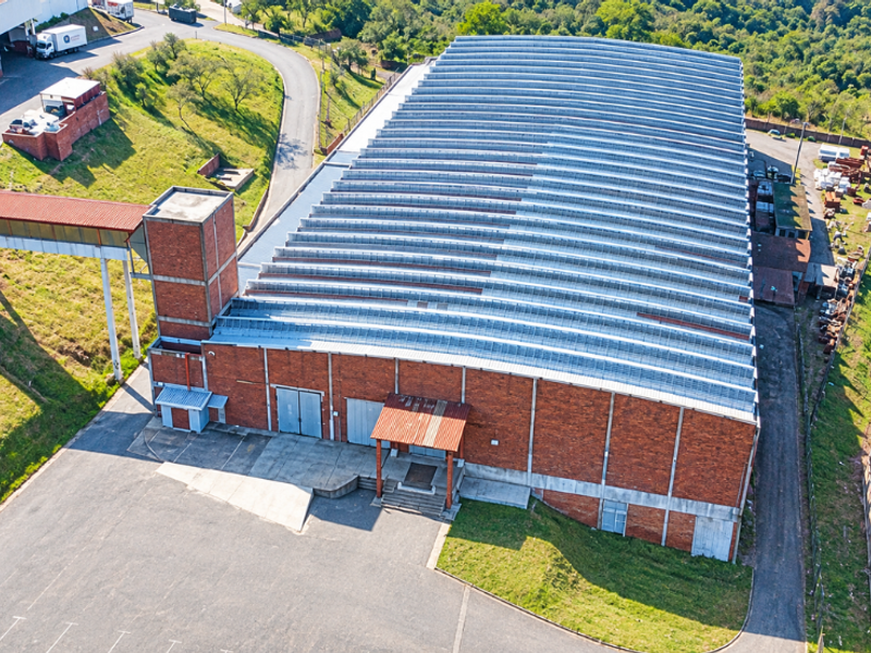 Aerial view of a large industrial warehouse facility featuring a corrugated metal roof, brick exterior, and dedicated loading access areas.