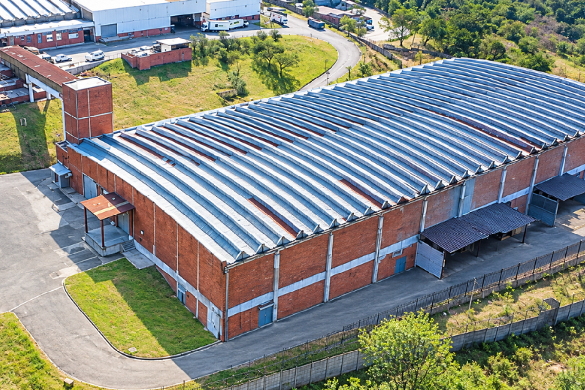 Aerial view of a large industrial warehouse facility featuring a corrugated metal roof, brick exterior, and dedicated loading bay access points.