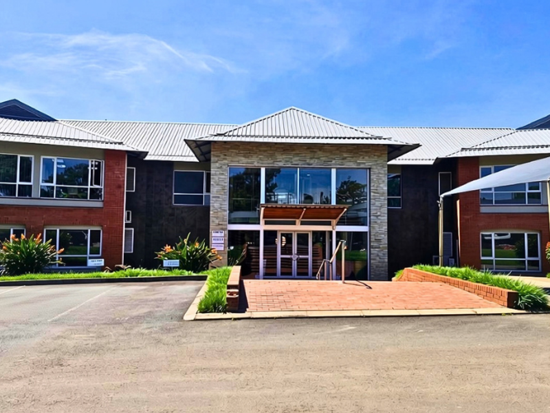Front elevation of a professional office building featuring a combination of brick and stone cladding, a metal roof, and a prominent glass entrance.