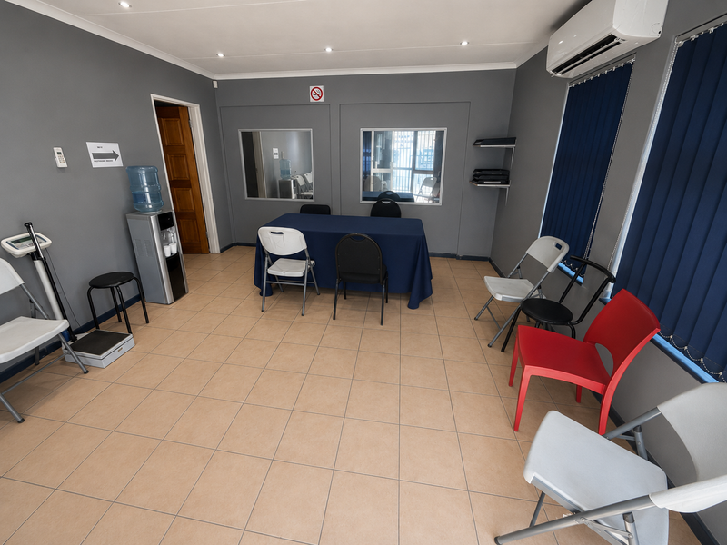 A functional office space featuring tiled flooring, recessed lighting, air conditioning, and internal windows, suitable for a professional work environment or meeting area.