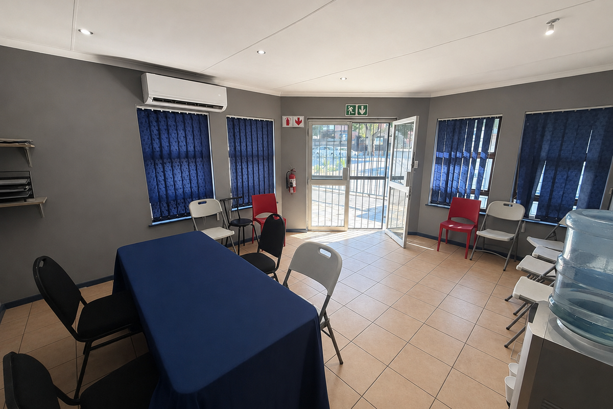 A functional office space featuring tiled flooring, recessed lighting, air conditioning, and secure access, suitable for a meeting room or professional workspace.