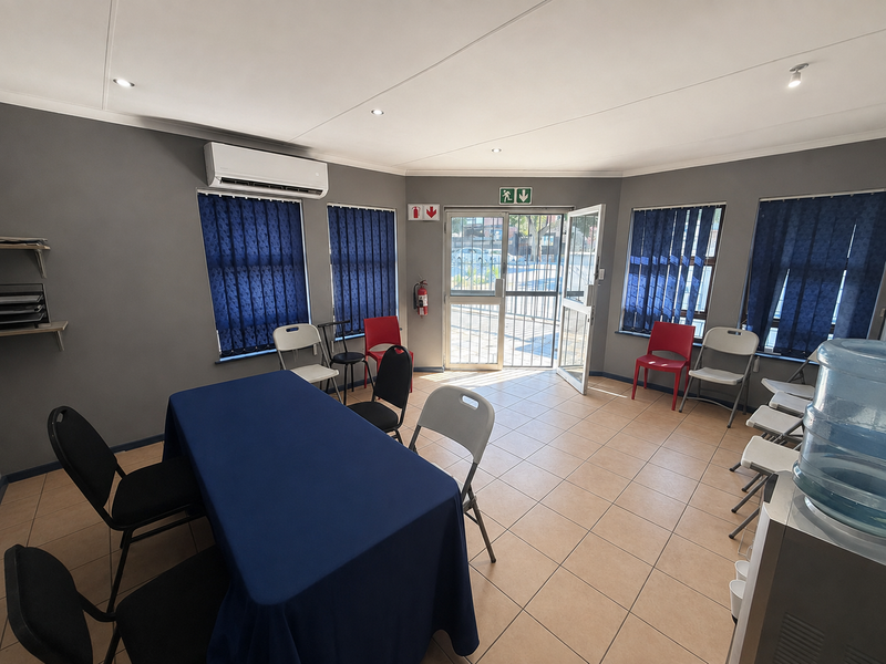 A functional office space featuring tiled flooring, recessed lighting, air conditioning, and secure access, suitable for a meeting room or professional workspace.