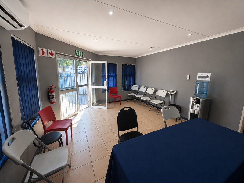 A functional office or waiting area featuring tiled flooring, recessed lighting, air conditioning, and large windows with vertical blinds.
