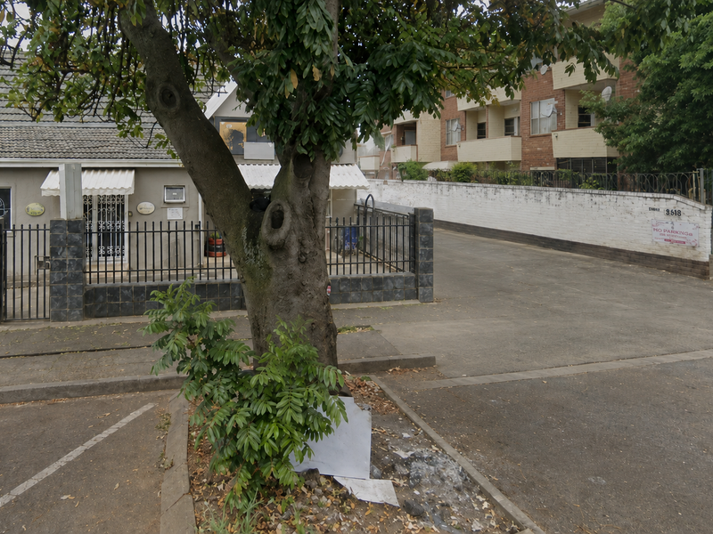 Front exterior view of a commercial property featuring a concrete driveway, security fencing, and gated access.