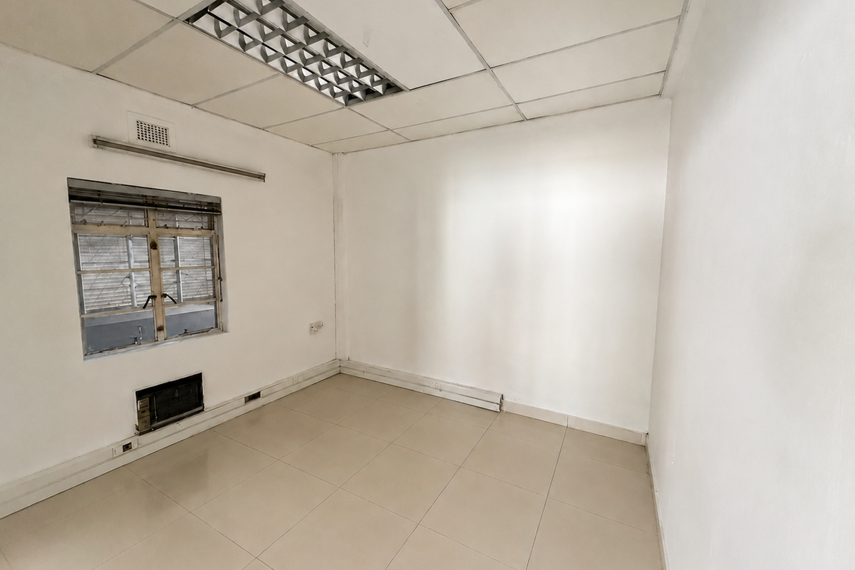 A vacant commercial office space featuring tiled flooring, a suspended ceiling with recessed lighting, and a built-in air conditioning unit.