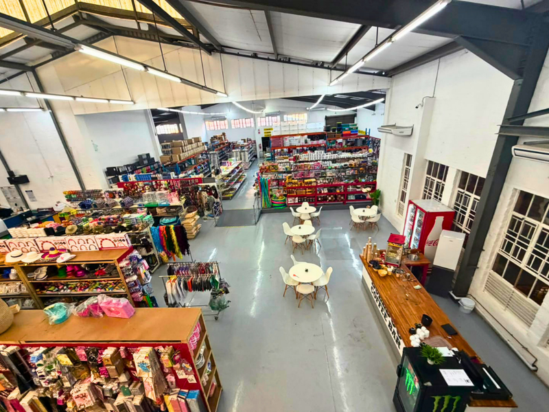 Spacious commercial open-plan retail area featuring high ceilings with exposed steel trusses, polished concrete flooring, and a dedicated service counter.
