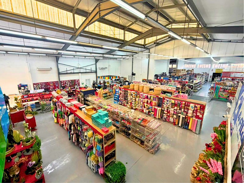 Spacious commercial retail floor featuring high exposed steel roof trusses, industrial lighting, skylights, and durable epoxy-coated concrete flooring.