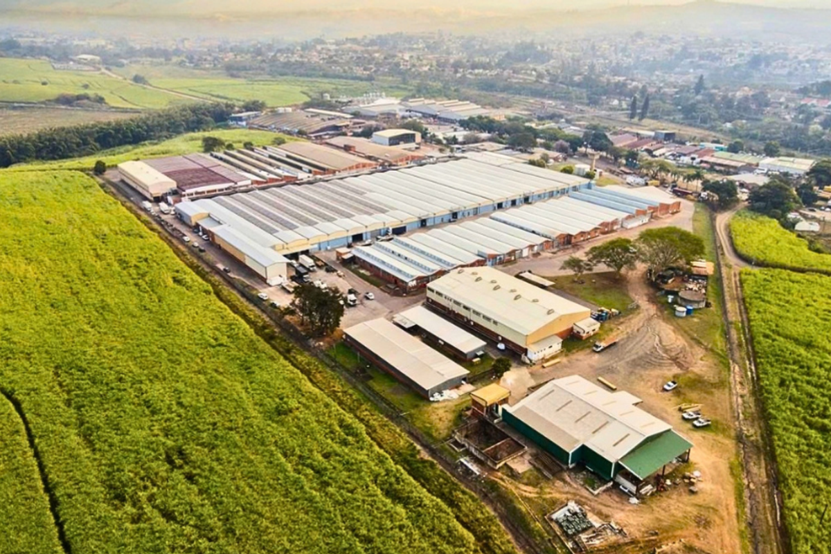 Aerial view of a large industrial warehouse complex featuring multiple connected buildings, metal roofing, and extensive surrounding land in a rural setting.